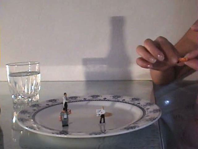 Vanesa has four shrunken men on her plate. She drenches them with syrup and then first teases them by licking them, and then eats them.
